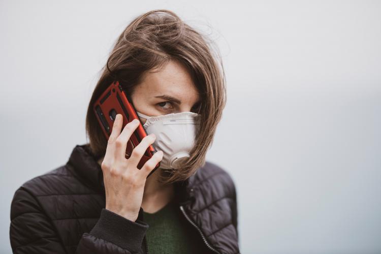 Symbolbild: Frau mit Atemschutzmaske und Telefon